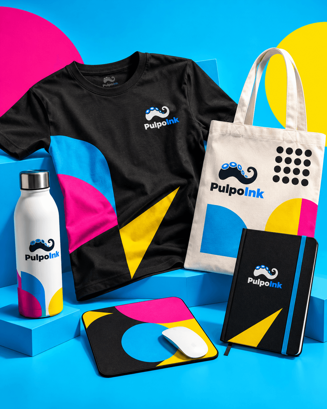 Playera negra, tote bag, termo, mousepad y libreta PulpoInk con gráficos cyan, magenta y amarillo